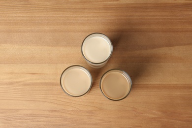 Photo of Glasses with protein shakes on wooden background, top view