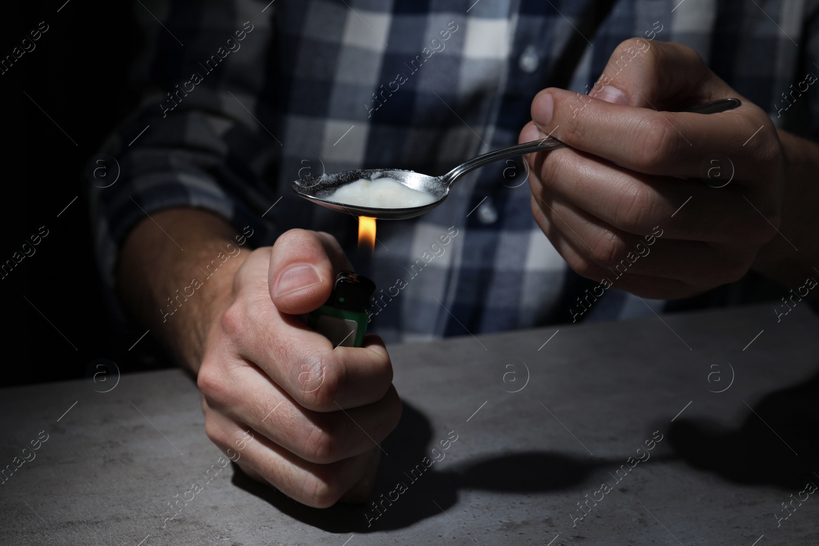 Photo of Man preparing drugs with spoon and lighter at grey table, closeup