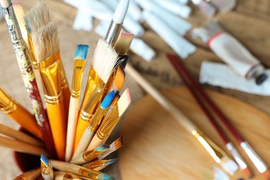 Photo of Many paintbrushes on wooden table, closeup. Space for text