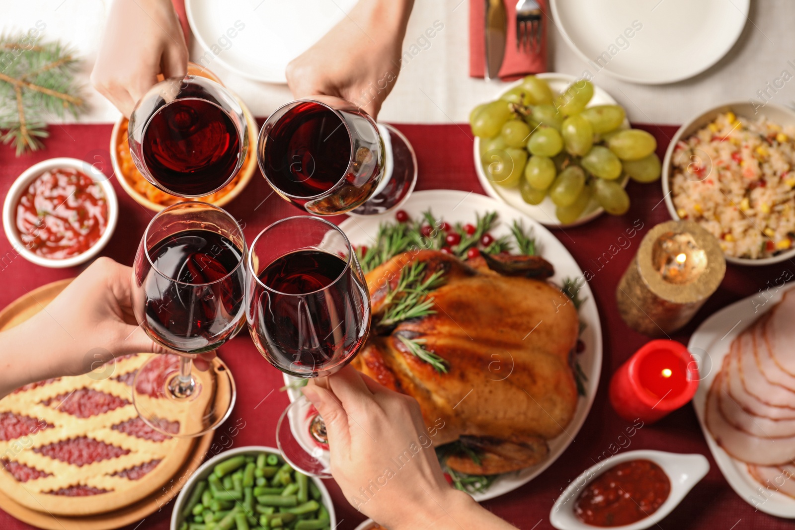 Photo of Women clinking glasses of wine over festive table with delicious roasted turkey, top view