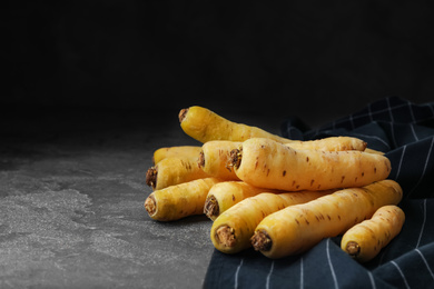 Raw white carrots on grey table against black background. Space for text