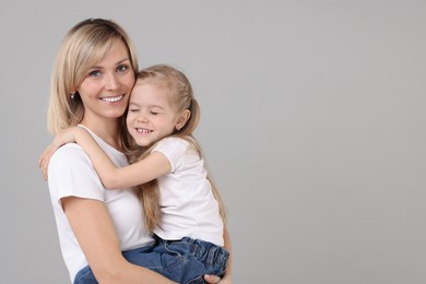 Family portrait of happy mother and daughter on grey background. Space for text