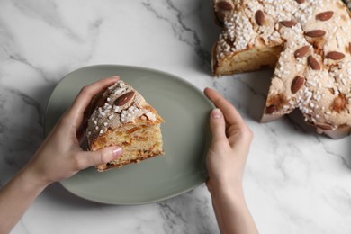 Woman with piece of delicious Italian Easter dove cake (traditional Colomba di Pasqua) at white marble table, above view