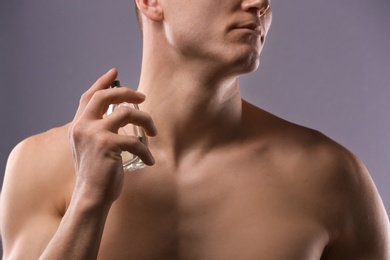 Photo of Handsome man using perfume on grey background, closeup