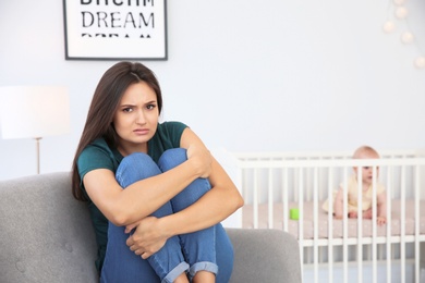 Photo of Young mother suffering from postnatal depression and little baby in room