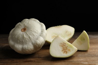 Whole and cut white pattypan squashes on wooden table against dark background