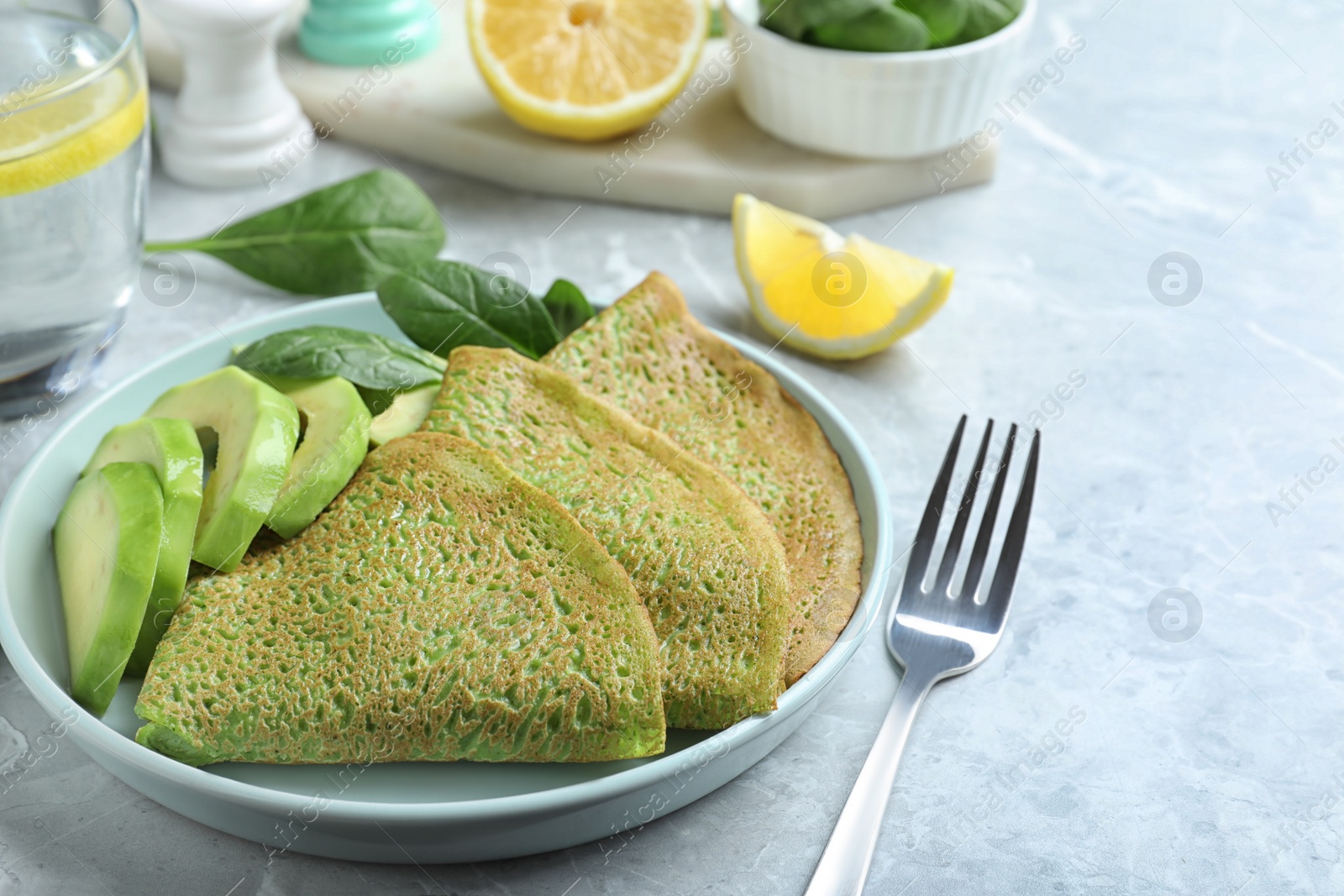 Photo of Delicious spinach crepes with avocado served on marble table