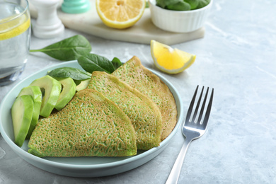 Photo of Delicious spinach crepes with avocado served on marble table