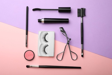 Photo of Flat lay composition with artificial eyelashes and accessories on color background