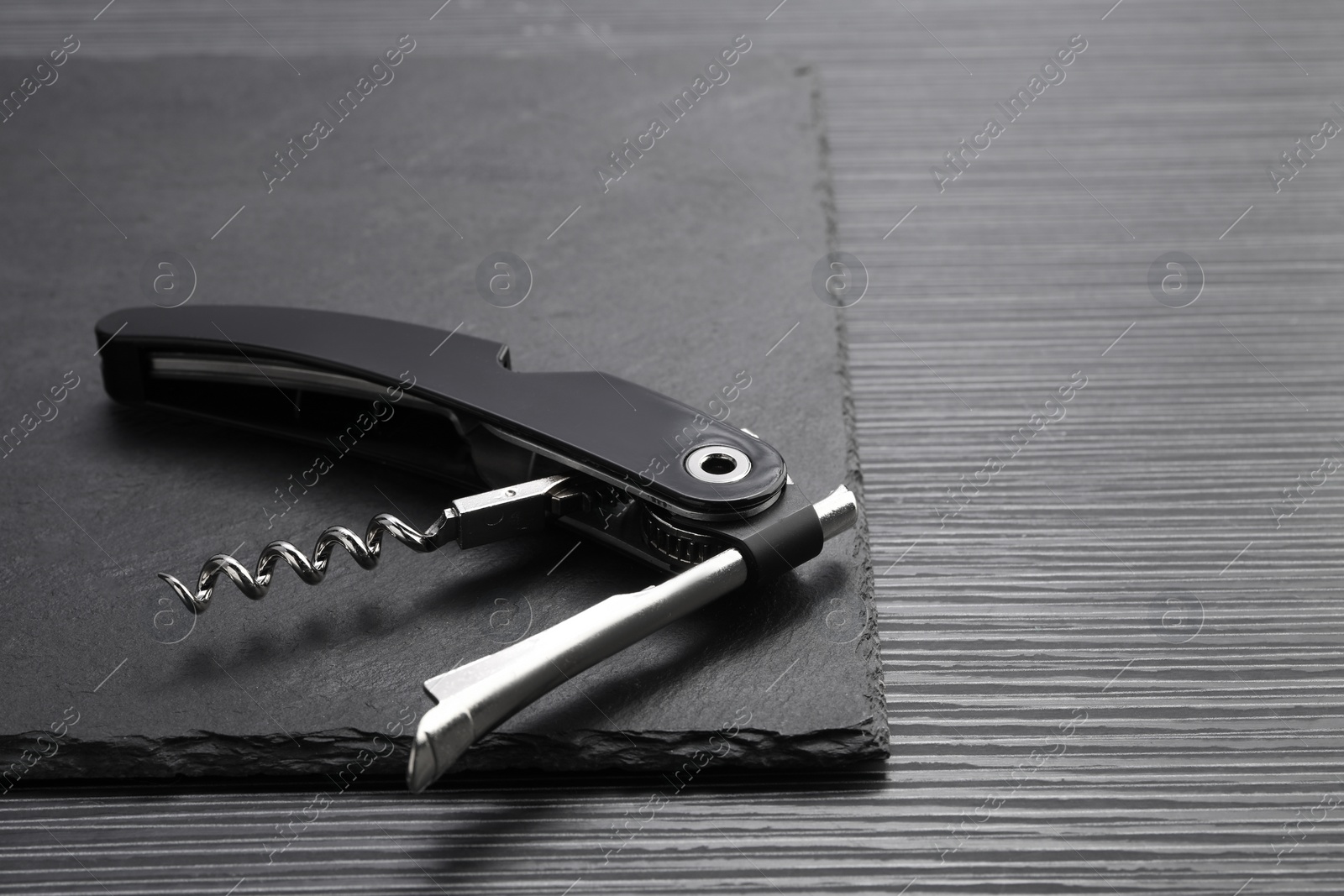Photo of One corkscrew (sommelier knife) on black wooden table. Space for text