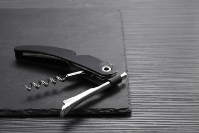 One corkscrew (sommelier knife) on black wooden table. Space for text