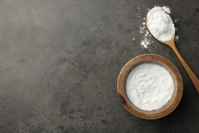 Photo of Baking powder in bowl and spoon on grey textured table, top view. Space for text