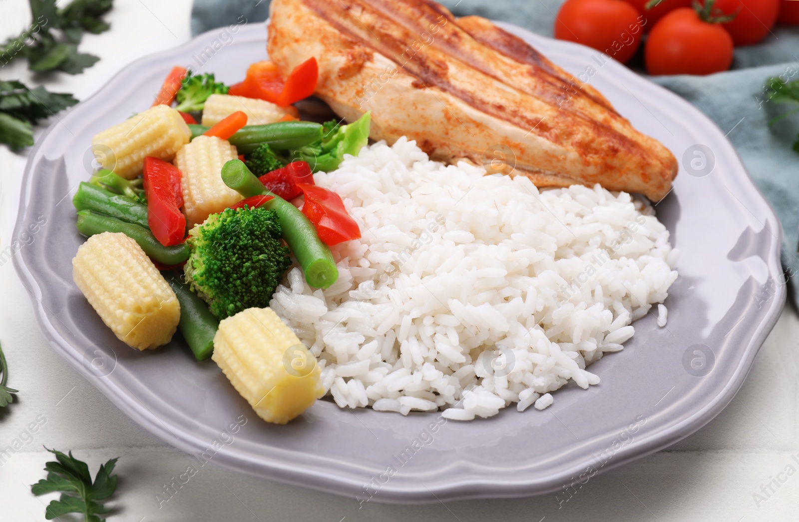 Photo of Grilled chicken breast and rice served with vegetables on white table, closeup