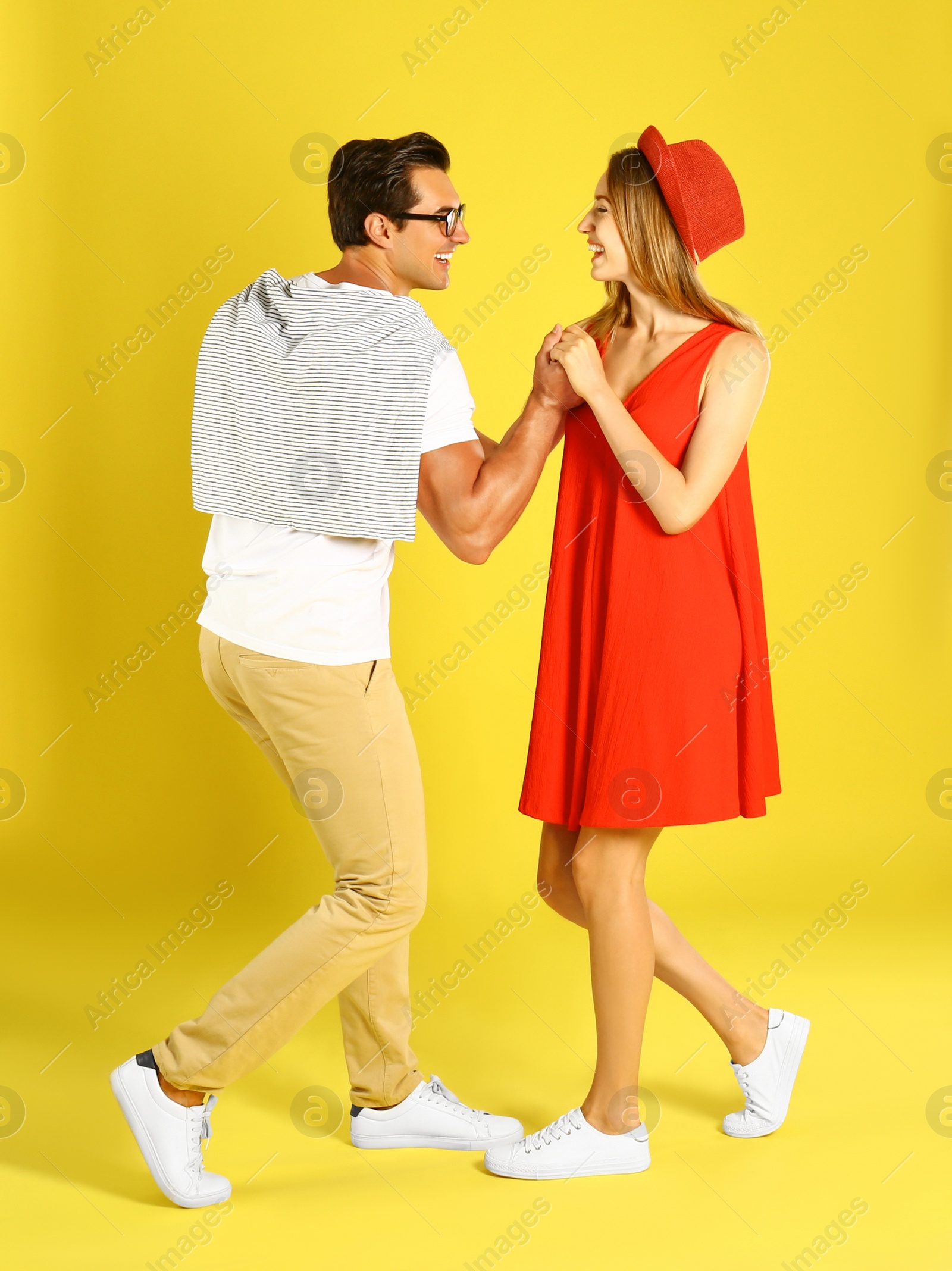 Photo of Beautiful young couple dancing on yellow background