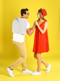 Beautiful young couple dancing on yellow background