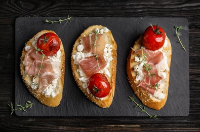 Flat lay composition with delicious bruschettas on black wooden table