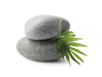 Grey spa stones and tropical leaf on white background