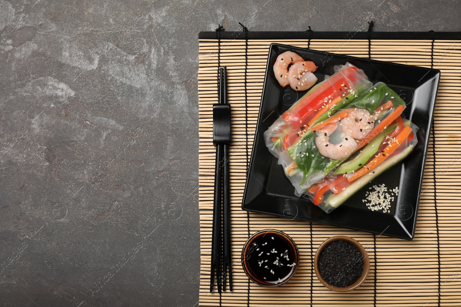 Photo of Delicious rolls wrapped in rice paper served on grey table, top view. Space for text
