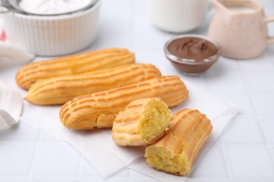 Photo of Delicious eclairs on white checkered table, closeup view