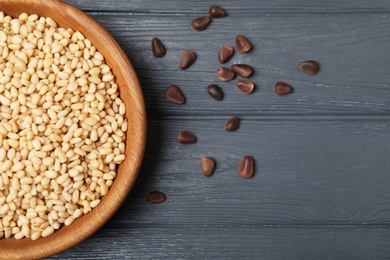 Photo of Dish with pine nuts on wooden background, top view. Space for text