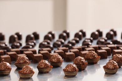 Photo of Many delicious chocolate candies on grey table. Production line