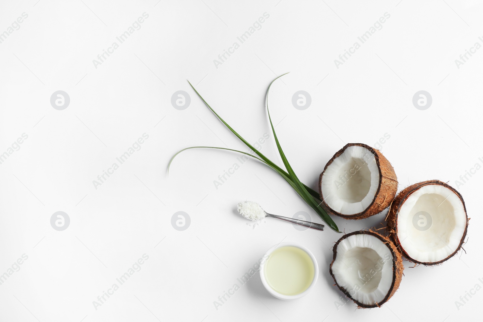 Photo of Bowl of natural organic oil and coconuts on white background, top view