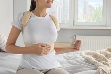 Photo of Woman with orthopedic corset sitting in bedroom, closeup