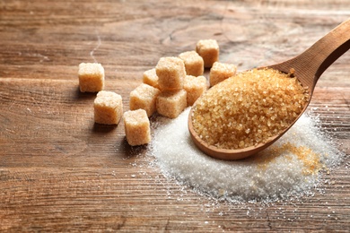 Spoon with brown sugar on wooden table