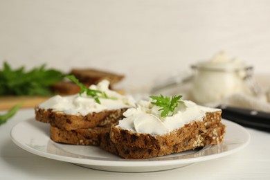 Photo of Bread with cream cheese and arugula on white wooden table