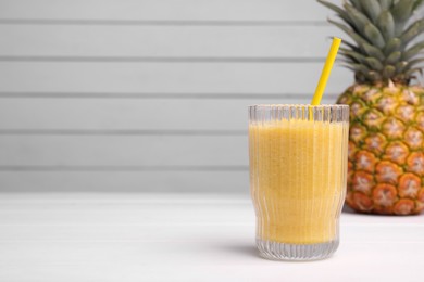 Tasty pineapple smoothie and fresh fruit on white table, space for text