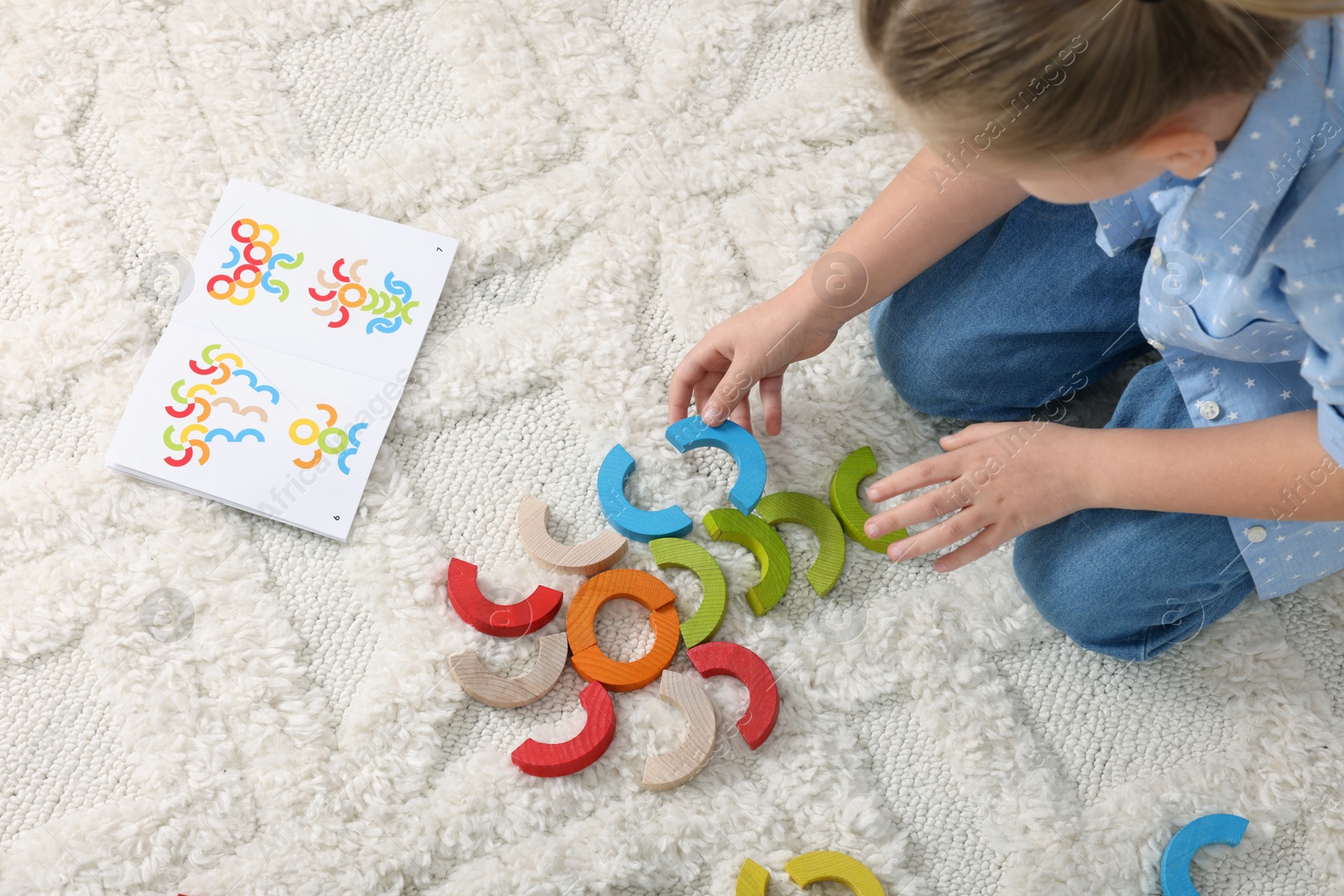 Photo of Motor skills development. Girl playing with colorful wooden arcs on carpet, above view