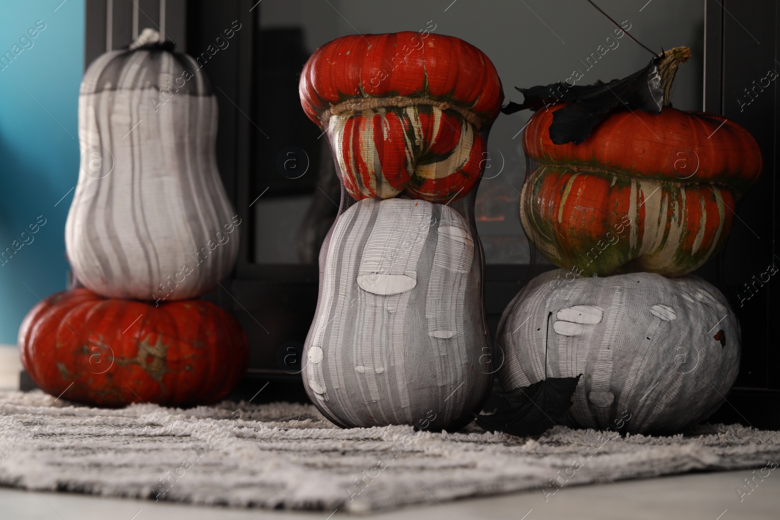 Photo of Colorful pumpkins on rug near fireplace. Halloween decorations