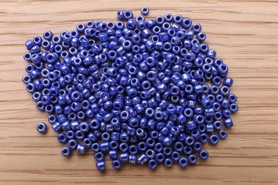 Photo of Pile of blue glass beads on wooden table, top view