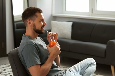 Photo of Man drinking delicious juice at home, space for text
