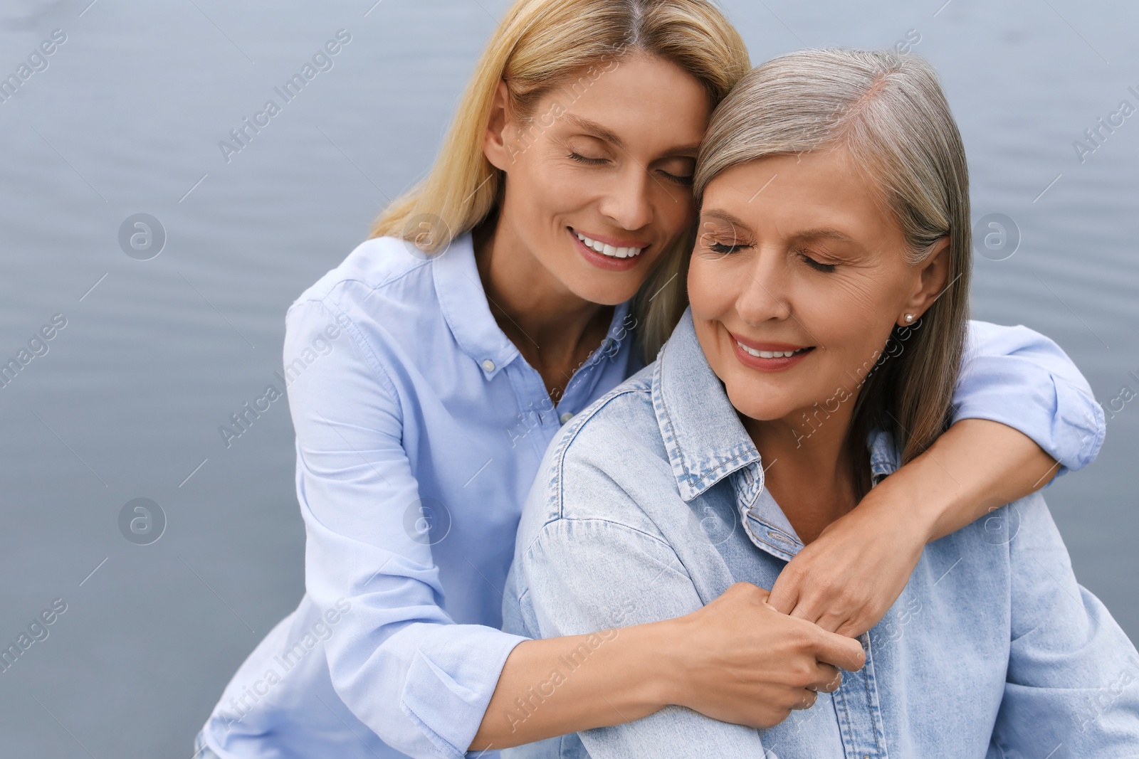 Photo of Happy mature mother and her daughter hugging near pond