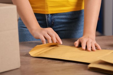 Post office worker sealing adhesive paper bag at counter indoors, closeup