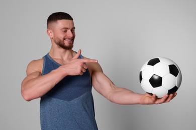 Photo of Athletic young man with soccer ball on light grey background