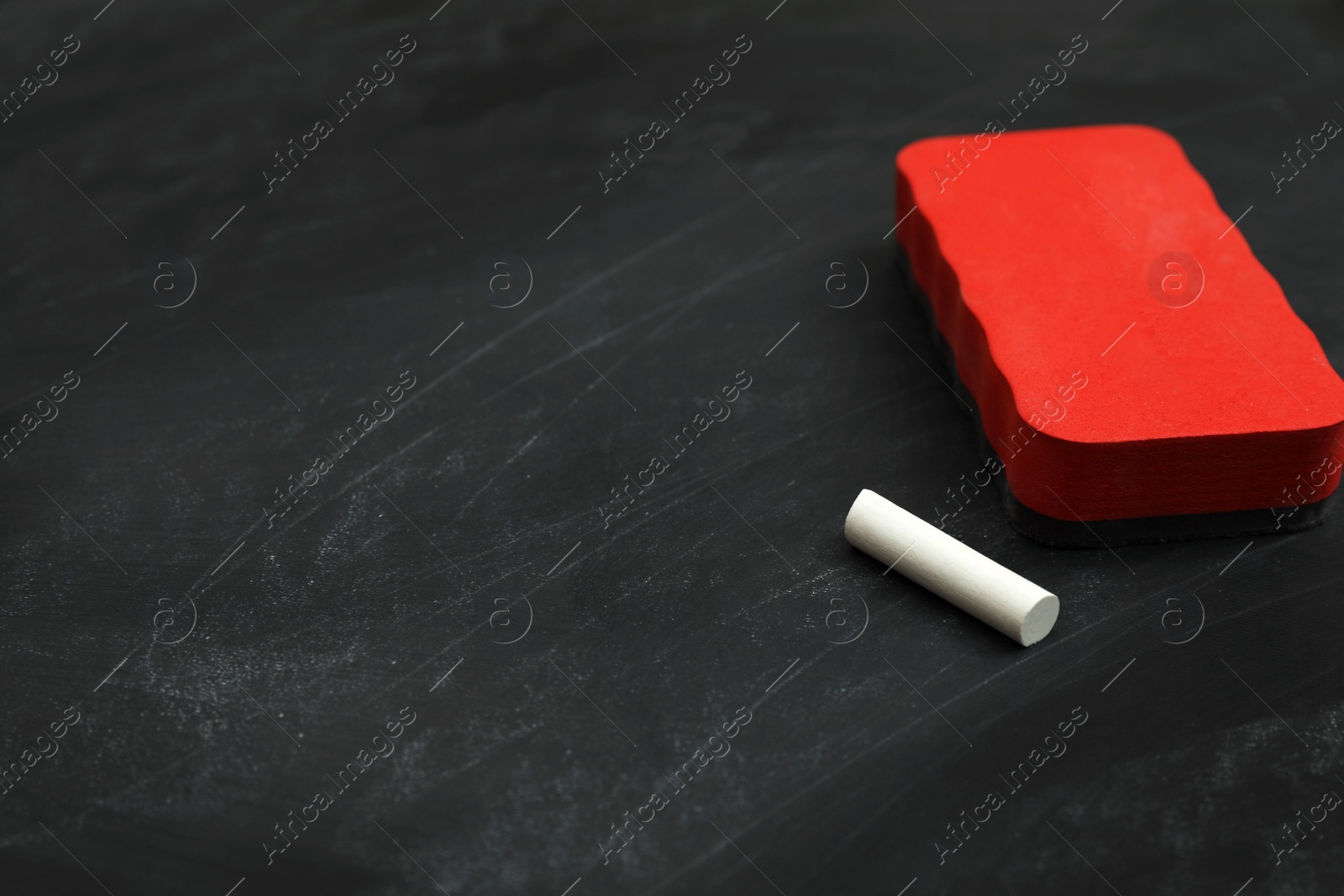 Photo of White chalk and duster on black board, space for text