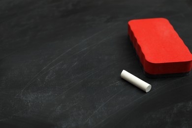 White chalk and duster on black board, space for text