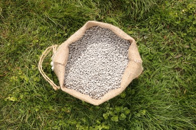 Photo of Fertilizer in bag on green grass outdoors, top view