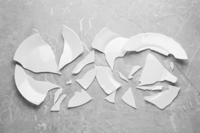 Photo of Two broken ceramic plates on light grey table, flat lay