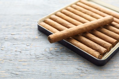 Photo of Many cigars in box on grey wooden table, space for text