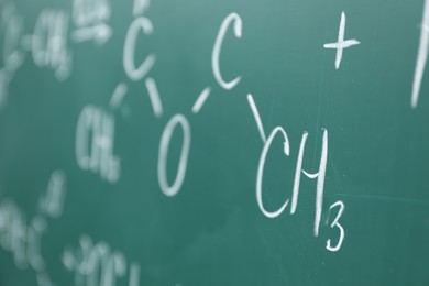 Chemical formulas written with chalk on green board, closeup