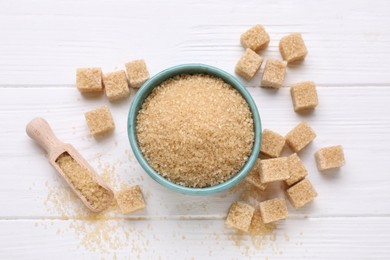 Photo of Different types of brown sugar on white wooden table, flat lay