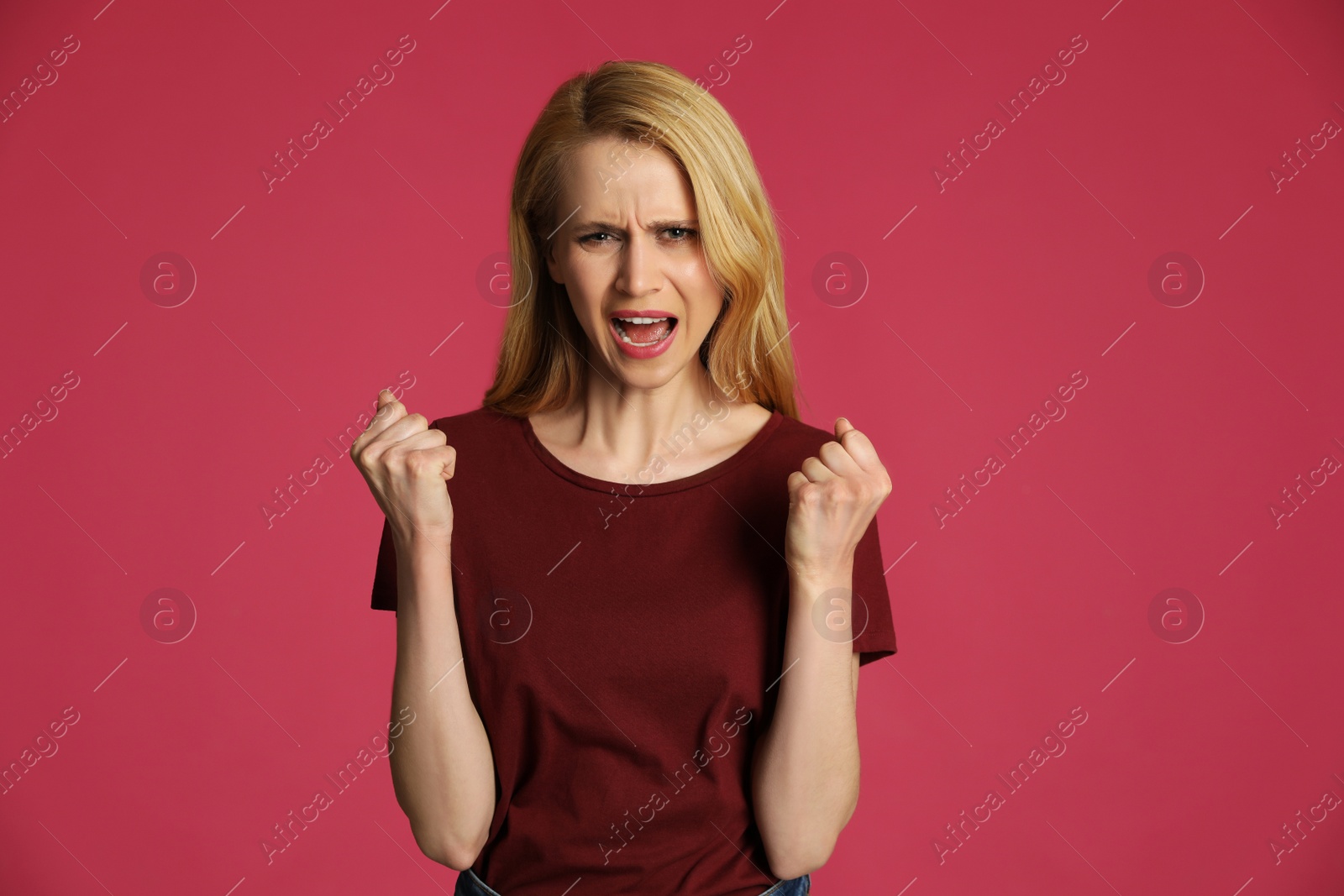 Photo of Angry young woman on pink background. Hate concept