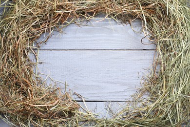 Photo of Frame made of dried hay on grey wooden table, top view. Space for text