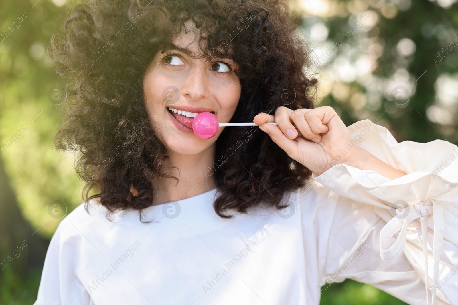 Photo of Beautiful woman in white blouse with lollipop outdoors