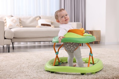 Photo of Cute baby making first steps with toy walker at home, space for text