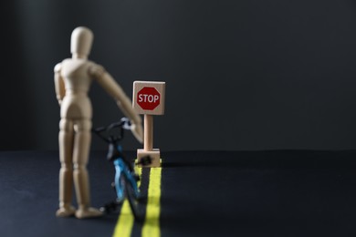 Photo of Development through barriers overcoming. Road Stop sign blocking way for wooden human figure with toy bicycle, space for text