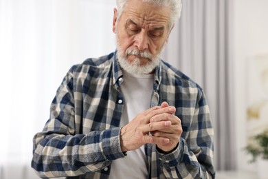 Arthritis symptoms. Man suffering from pain in fingers at home